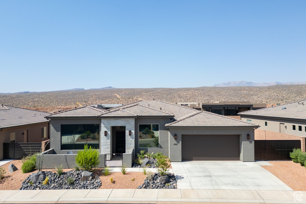 Prairie-style home with a garage, a mountain view, stucco siding, and concrete driveway