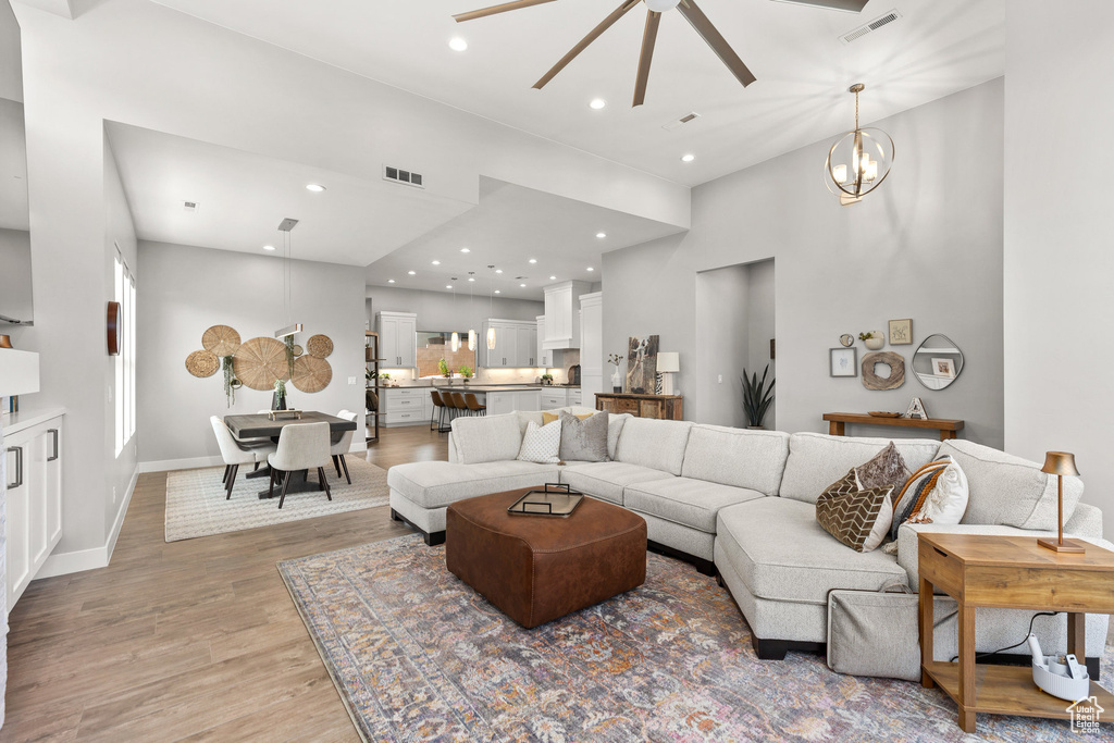 Living area with ceiling fan, light wood-style flooring, a high ceiling, and recessed lighting
