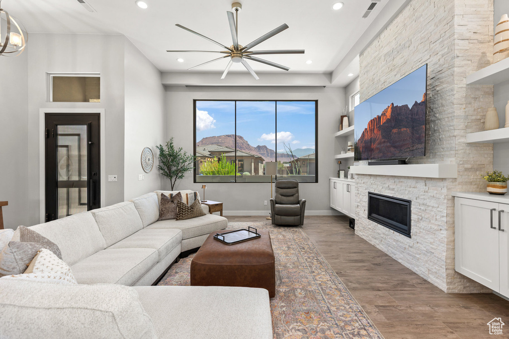 Living area featuring wood finished floors, a stone fireplace, ceiling fan, and recessed lighting