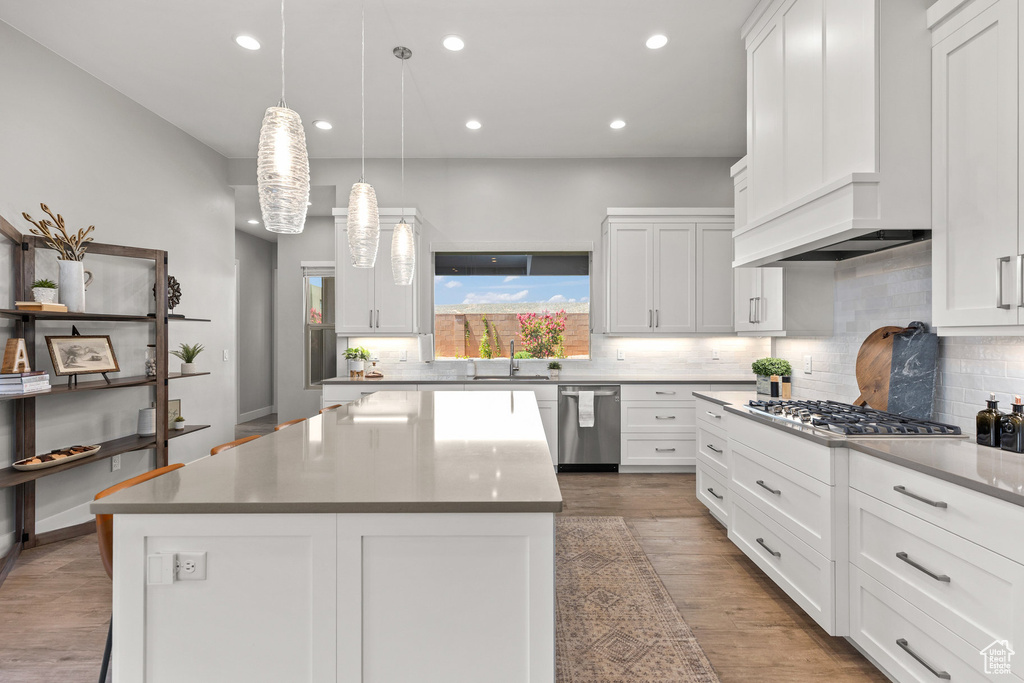 Kitchen featuring stainless steel appliances, decorative backsplash, white cabinetry, a center island, and recessed lighting