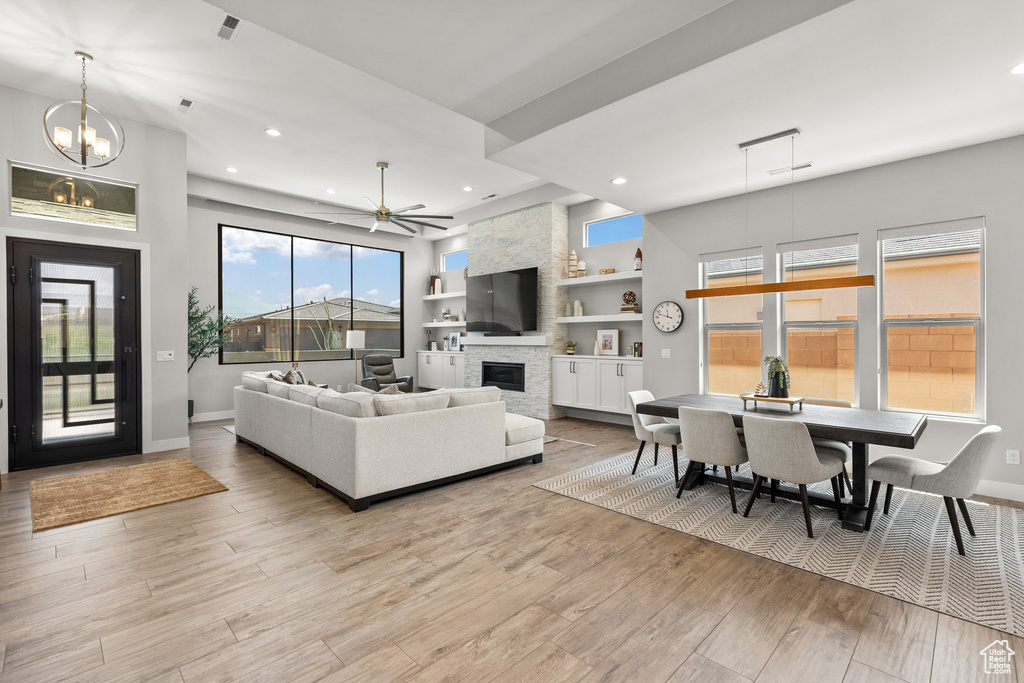 Living area featuring a stone fireplace, light wood-style floors, recessed lighting, built in features, and ceiling fan