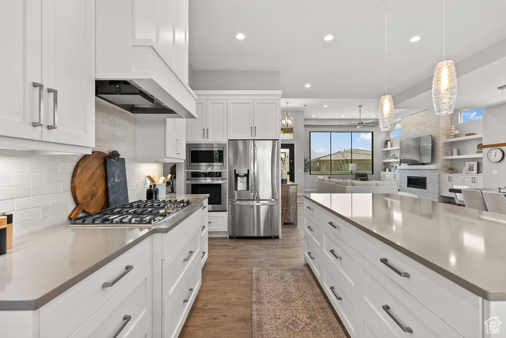 Kitchen featuring stainless steel appliances, a fireplace, a ceiling fan, recessed lighting, and tasteful backsplash