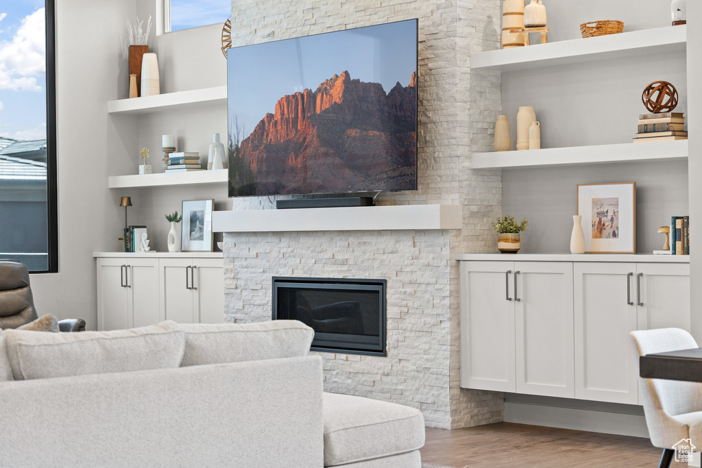 Living room featuring wood finished floors, plenty of natural light, and a stone fireplace