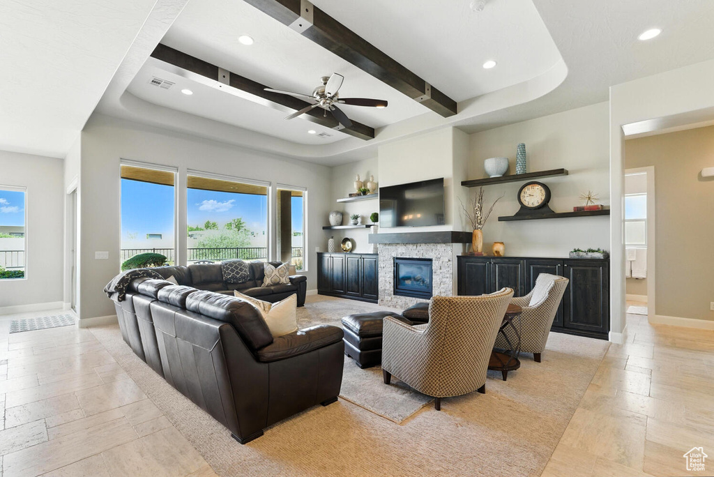 Living room with healthy amount of natural light, recessed lighting, a fireplace, ceiling fan, and stone tile floors