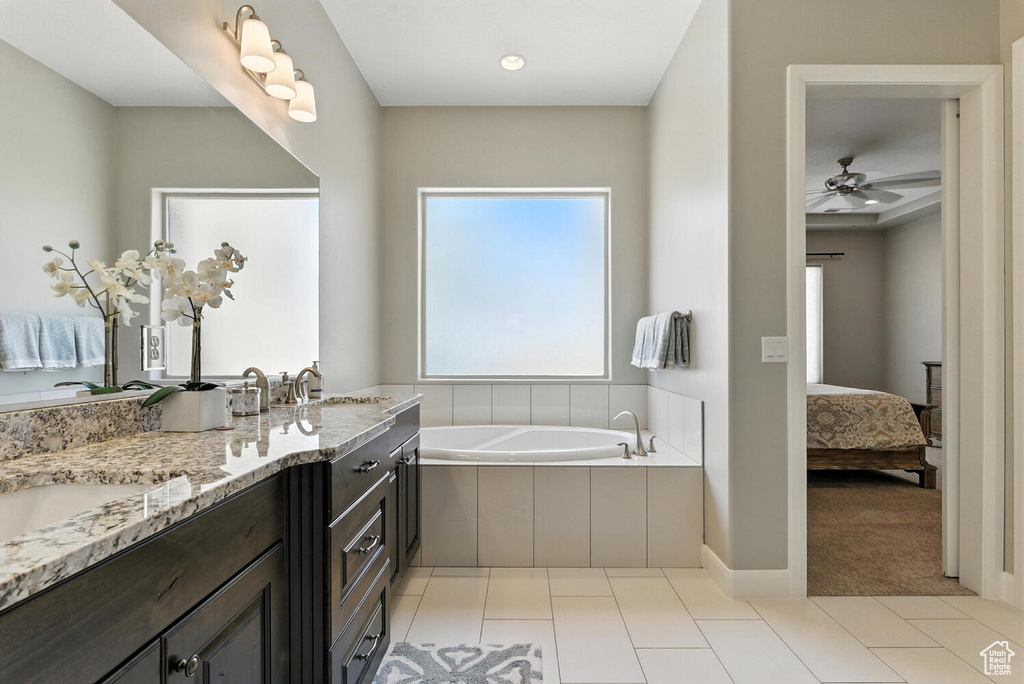 Ensuite bathroom featuring a bath, double vanity, tile patterned floors, and ceiling fan