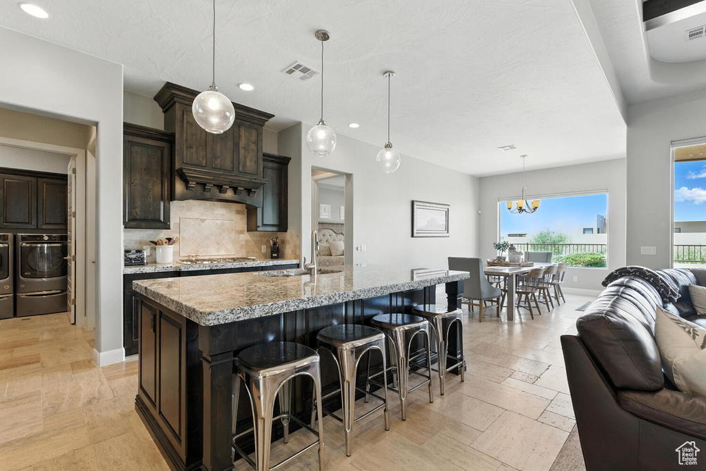 Kitchen featuring open floor plan, backsplash, dark brown cabinets, recessed lighting, and a breakfast bar area