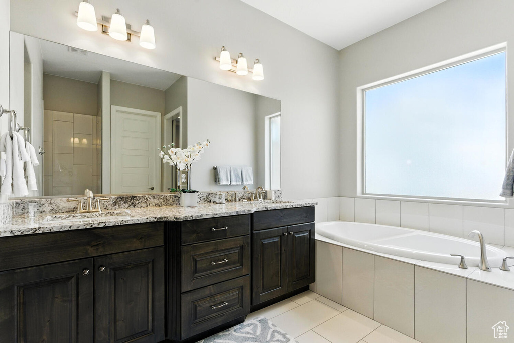 Full bathroom with double vanity, a garden tub, tile patterned floors, and a tile shower
