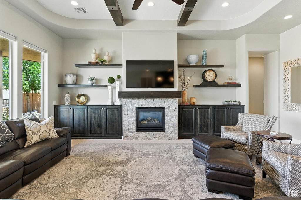 Living area featuring beam ceiling, a stone fireplace, recessed lighting, and ceiling fan