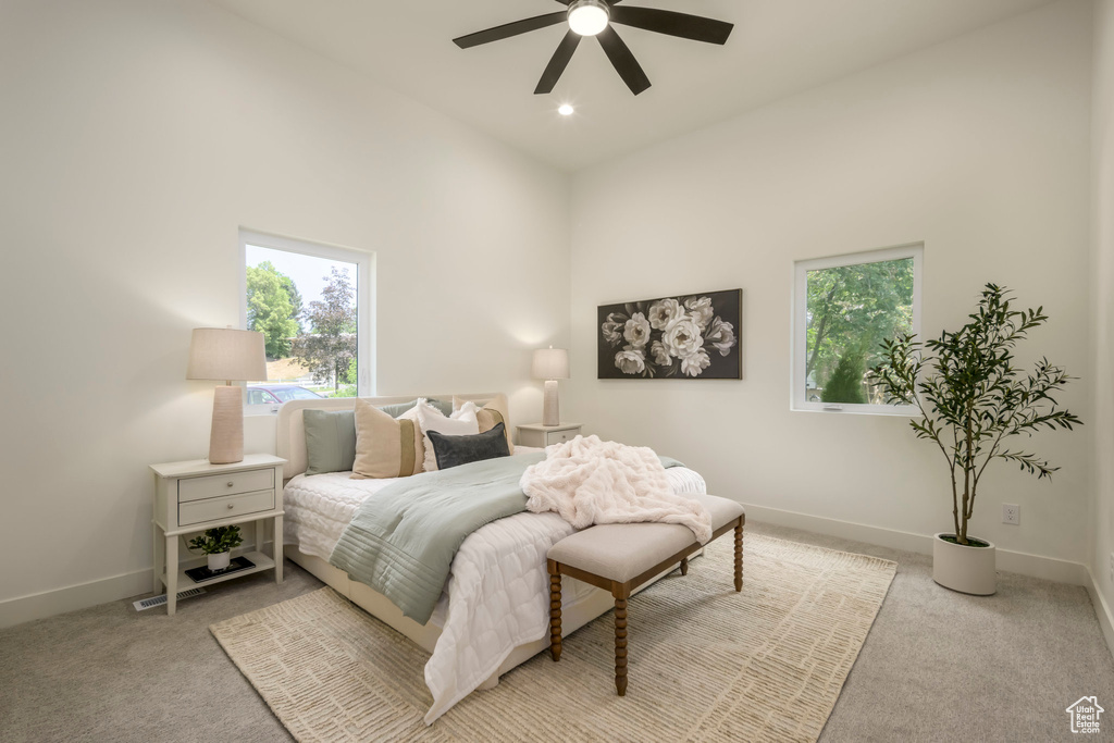 Bedroom featuring light colored carpet, a high ceiling, and ceiling fan