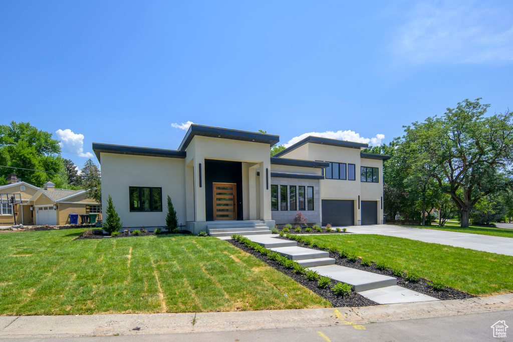 Modern home with a garage, driveway, stucco siding, and a front yard