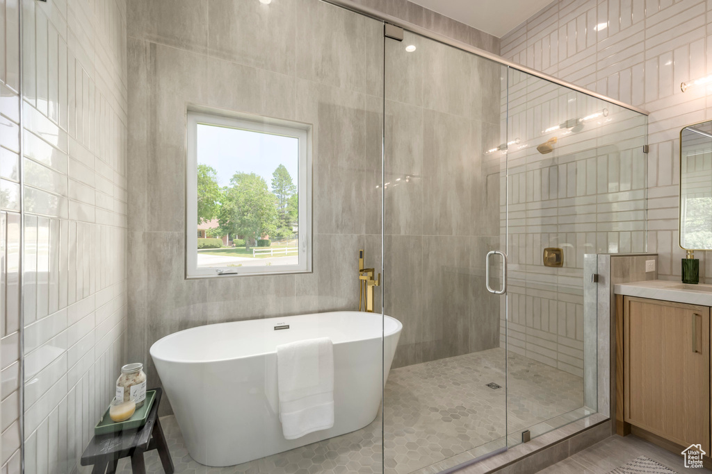 Full bath with a freestanding bath, a stall shower, vanity, and tile walls