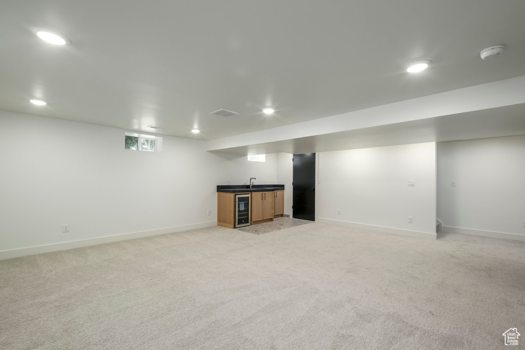 Basement featuring beverage cooler, wet bar, light carpet, and recessed lighting