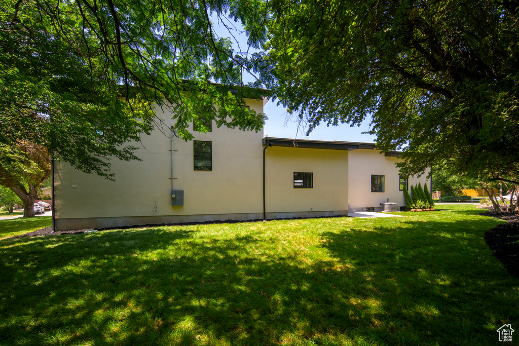Rear view of house with stucco siding and a yard