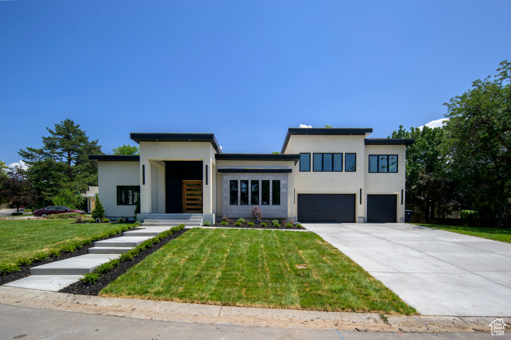 Contemporary house with an attached garage, stucco siding, concrete driveway, and a front lawn