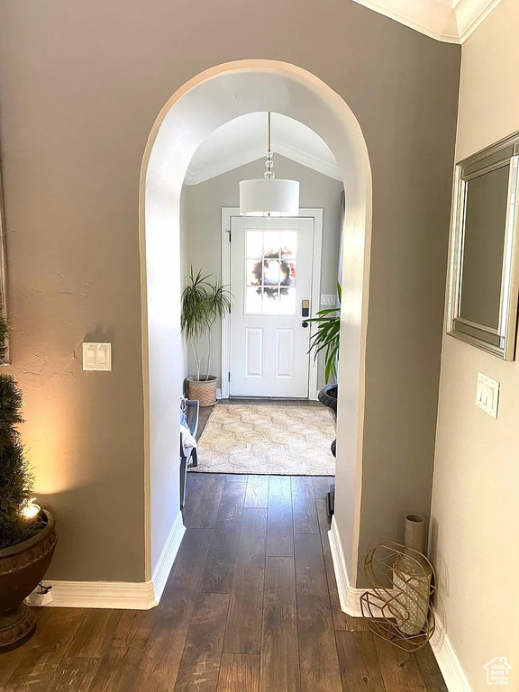 Entryway featuring arched walkways, dark wood-style floors, and crown molding