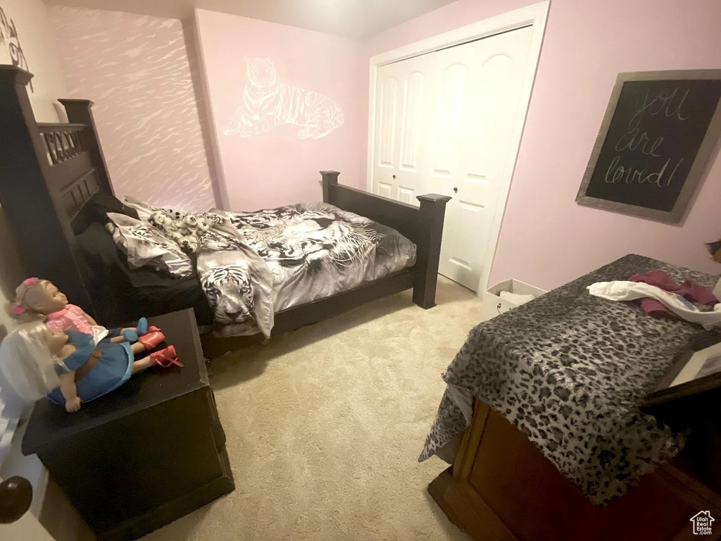 Bedroom with light colored carpet and a closet