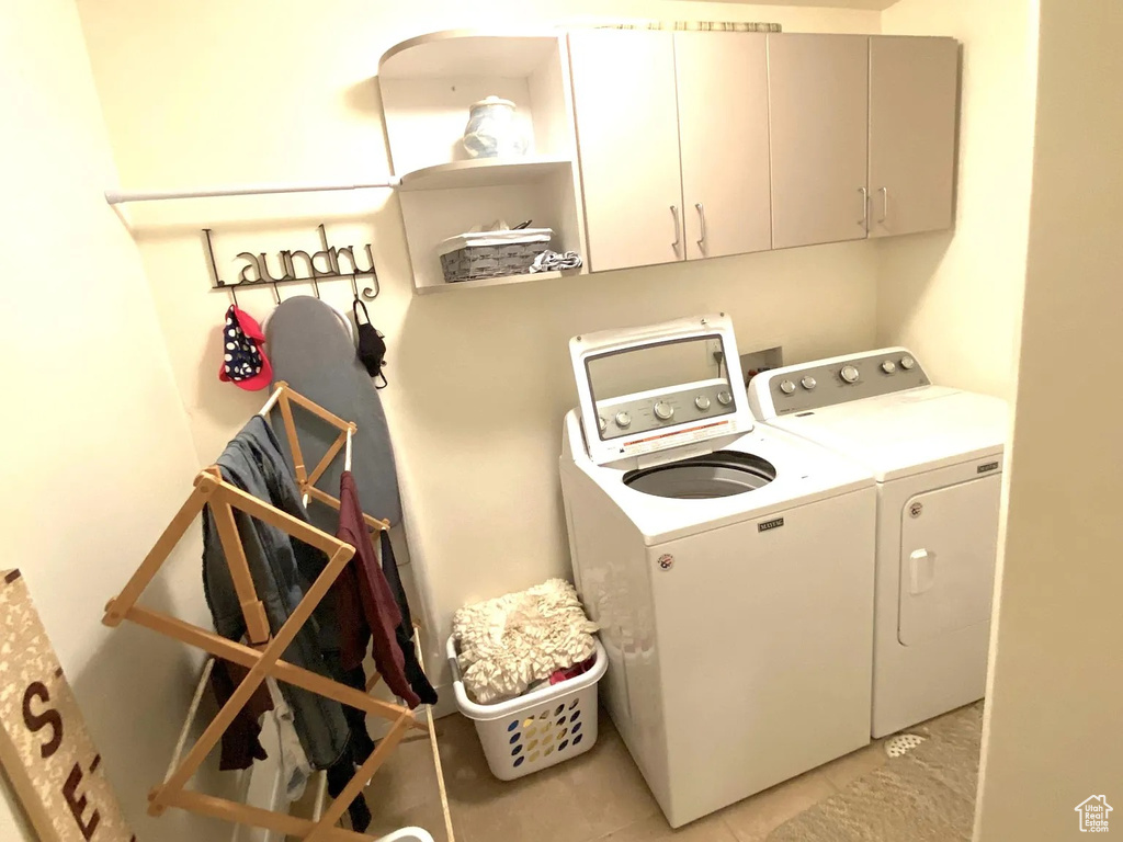 Washroom with cabinet space, washing machine and clothes dryer, and light tile patterned floors