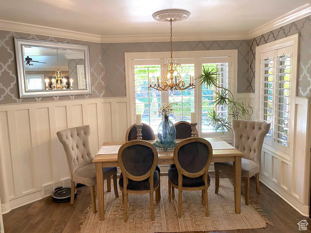 Dining room featuring a chandelier, a decorative wall, a wainscoted wall, dark wood-style flooring, and wallpapered walls