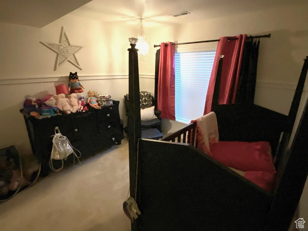 Bedroom with light carpet and a wainscoted wall