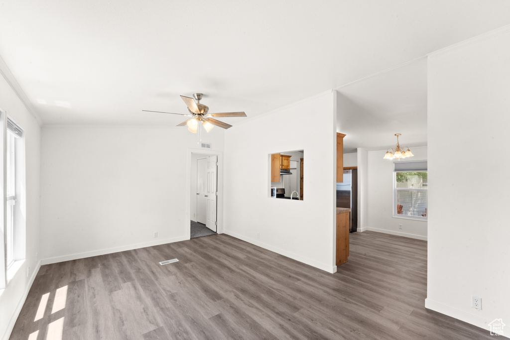 Unfurnished room with a chandelier, wood finished floors, a ceiling fan, and crown molding