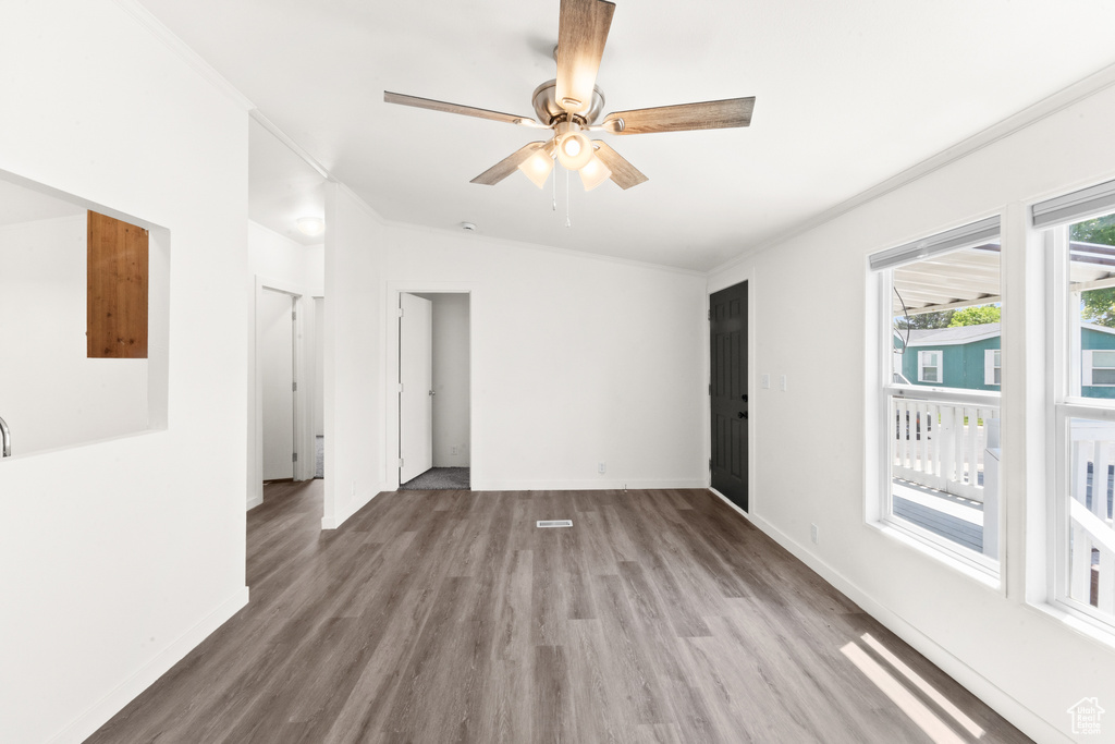 Empty room with wood finished floors, ceiling fan, and ornamental molding