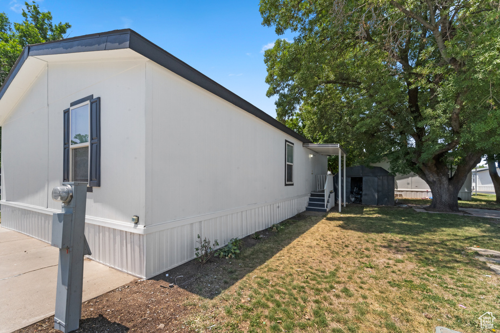 View of home's exterior featuring a storage unit and a lawn