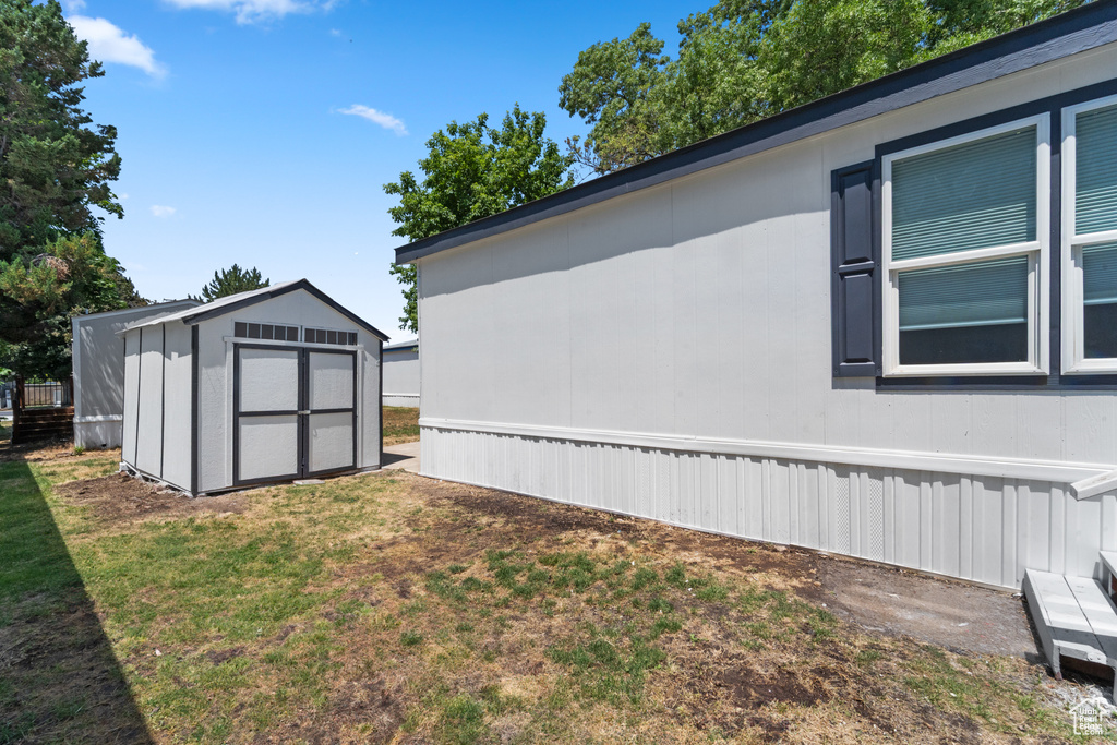 View of property exterior featuring a storage shed and a lawn