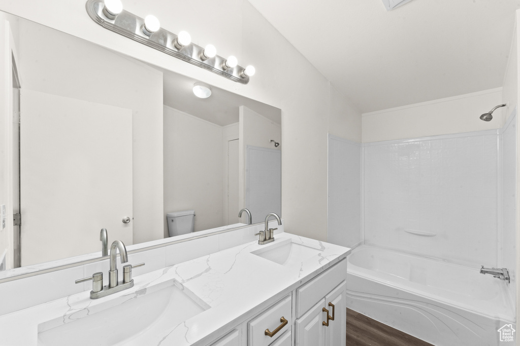 Bathroom with double vanity, tub / shower combination, and wood finished floors