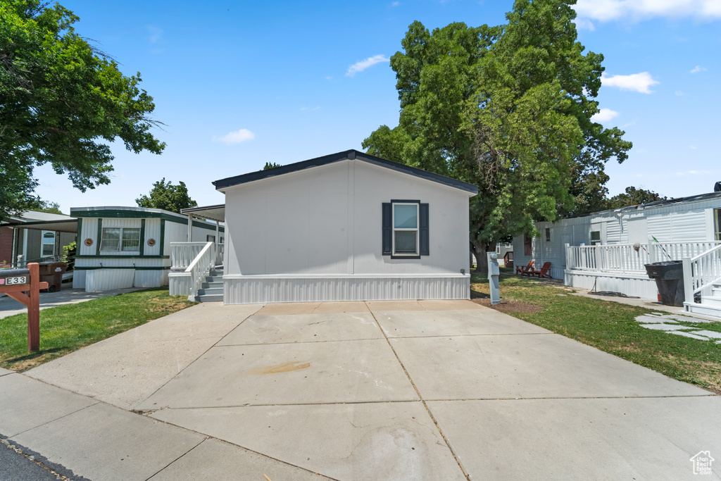 Manufactured / mobile home featuring driveway, a front lawn, and a porch