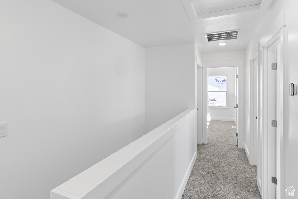 Hallway featuring light colored carpet and attic access