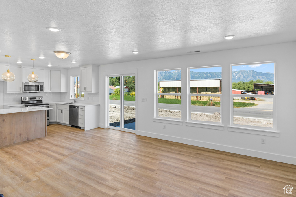 Kitchen featuring appliances with stainless steel finishes, light countertops, light wood-style floors, recessed lighting, and a textured ceiling
