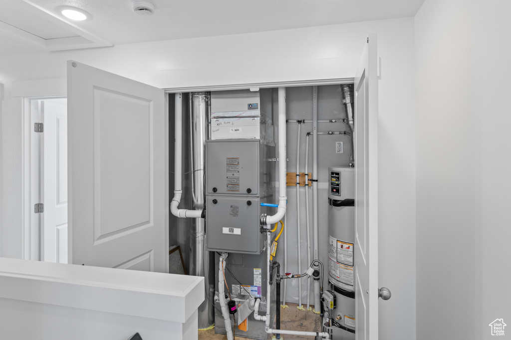 Utility room featuring water heater and heating unit