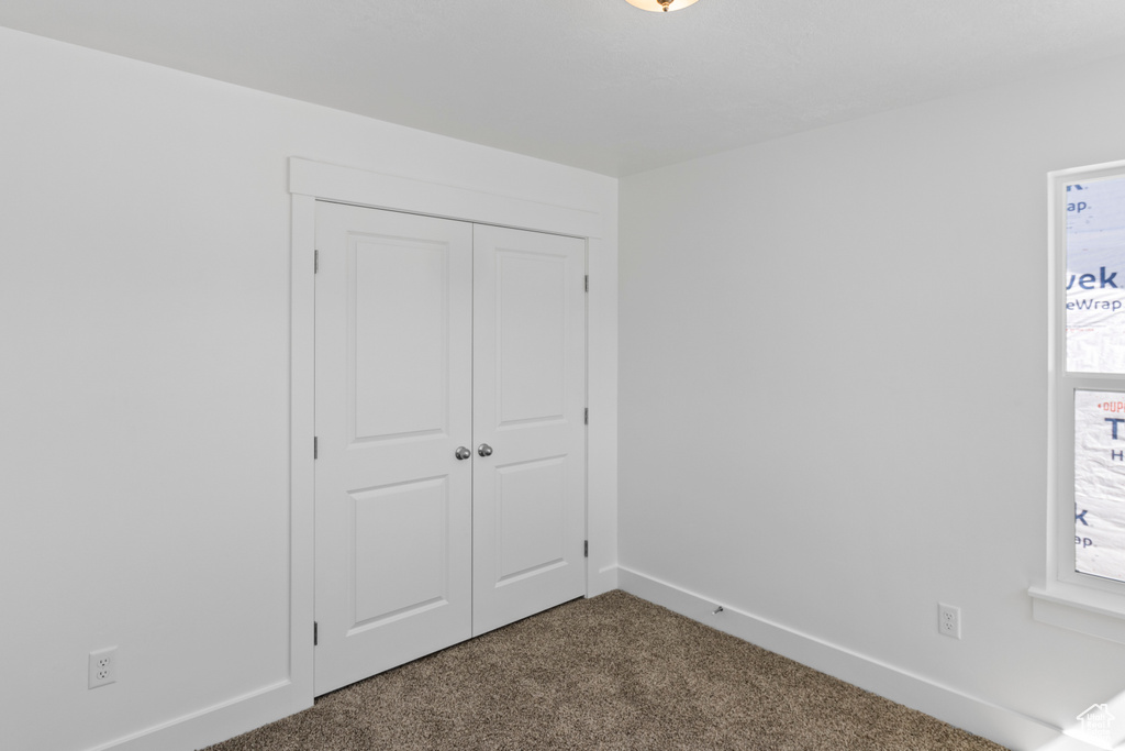 Unfurnished bedroom with dark colored carpet and a closet