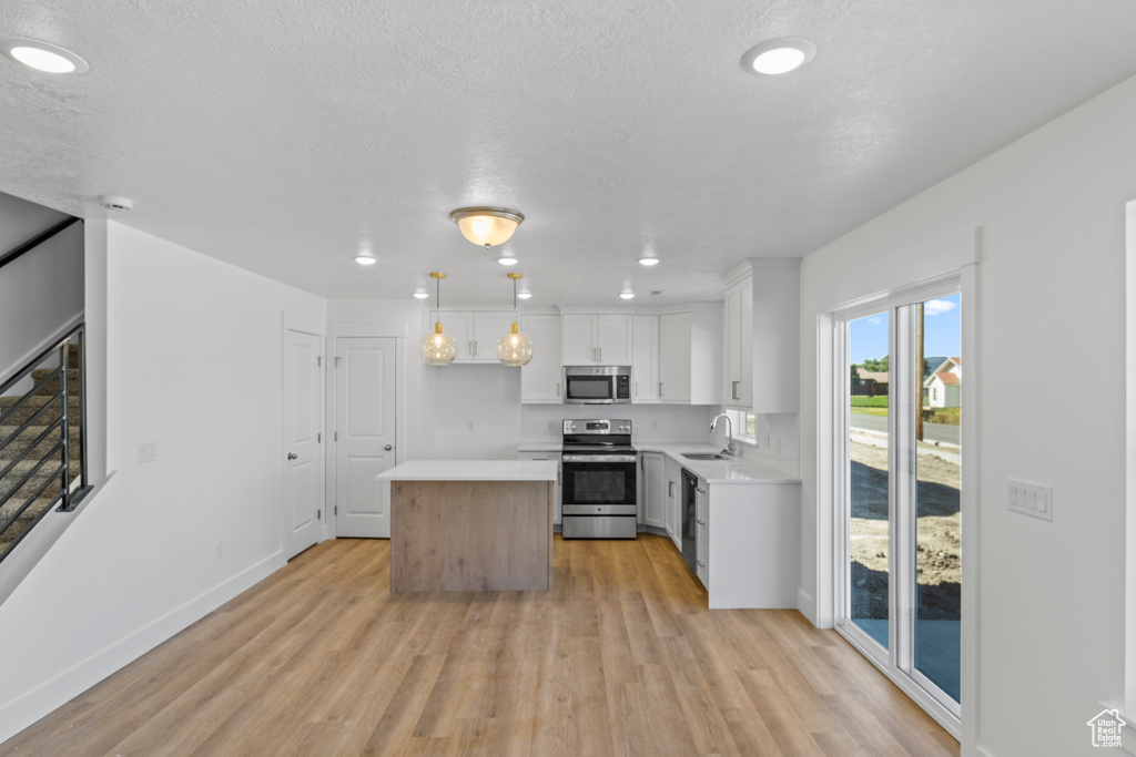 Kitchen with appliances with stainless steel finishes, light wood-type flooring, light countertops, and recessed lighting
