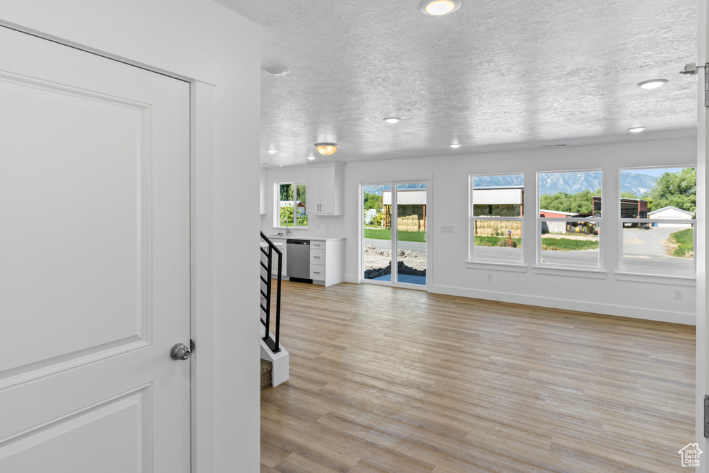 Unfurnished living room featuring a textured ceiling and light wood-style flooring