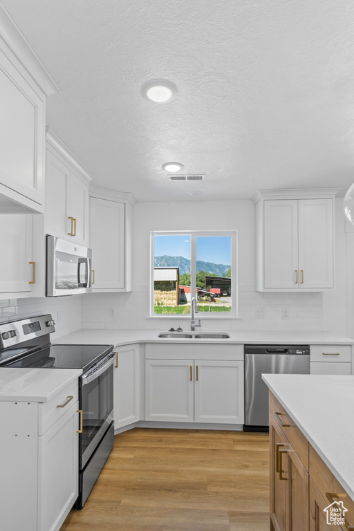 Kitchen featuring stainless steel appliances, light countertops, white cabinets, a textured ceiling, and recessed lighting