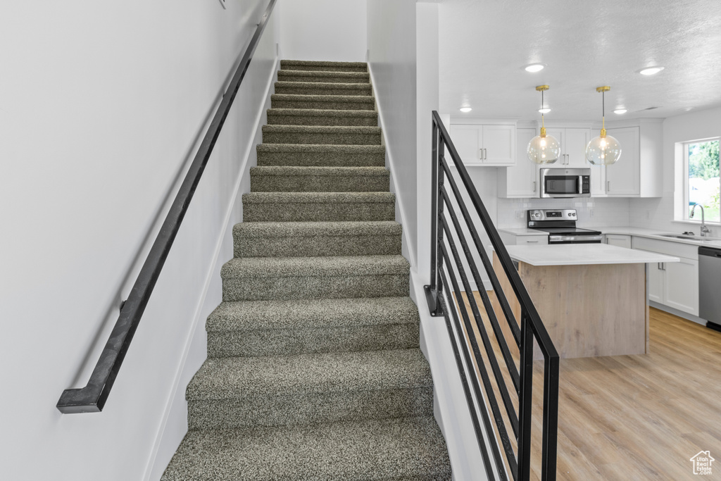 Stairway featuring wood finished floors and recessed lighting