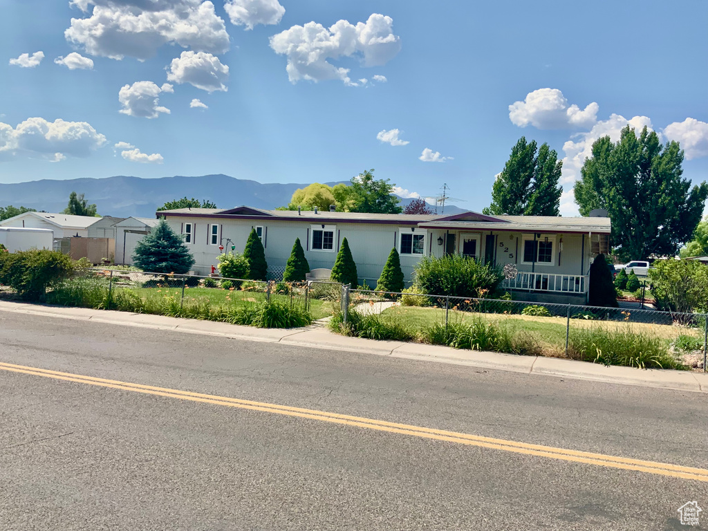 Ranch-style house featuring a porch, a mountain view, and a fenced front yard