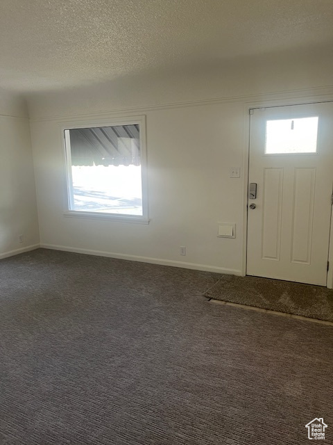 Entryway with dark carpet and a textured ceiling