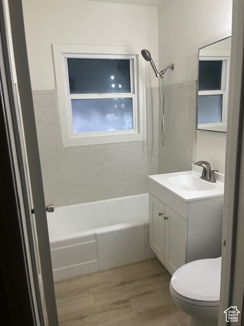 Bathroom with vanity, bathtub / shower combination, wood finished floors, and a textured wall