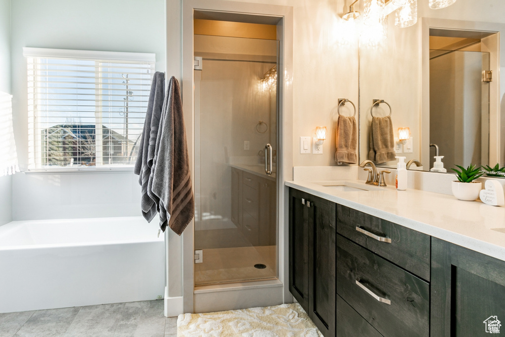 Full bath featuring a stall shower, a garden tub, double vanity, tile patterned floors, and a chandelier