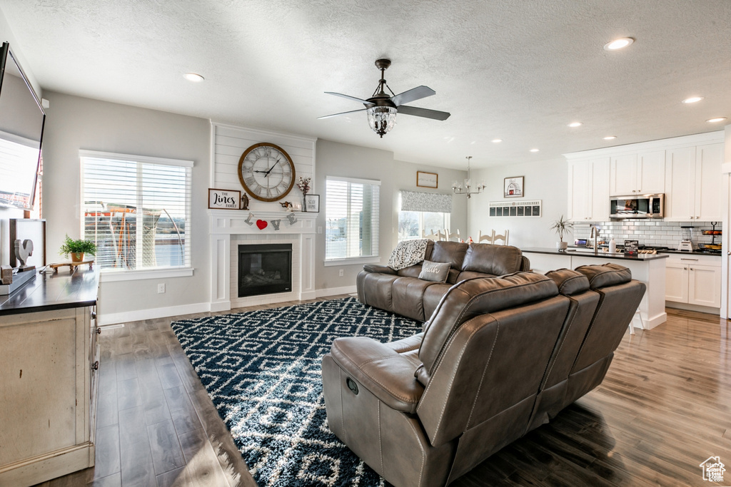 Living room with a ceiling fan, healthy amount of natural light, a textured ceiling, wood finished floors, and recessed lighting