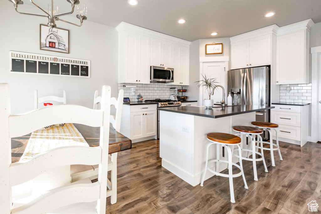 Kitchen featuring stainless steel appliances, dark countertops, decorative backsplash, and recessed lighting