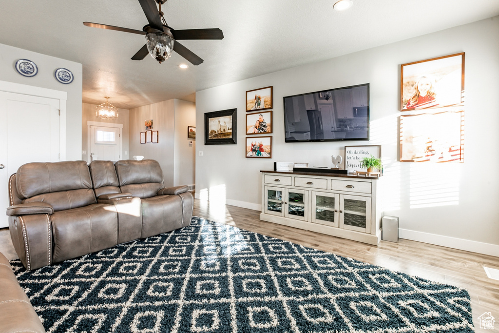 Living room with ceiling fan, wood finished floors, a chandelier, and recessed lighting
