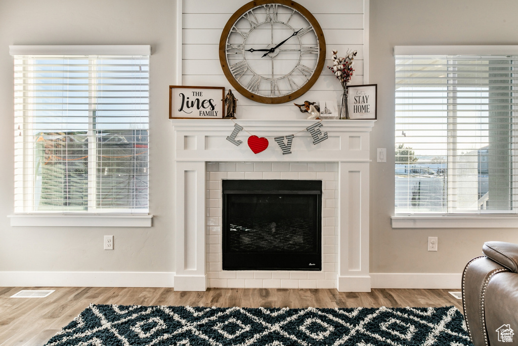 Living room featuring wood finished floors, a tiled fireplace, and plenty of natural light