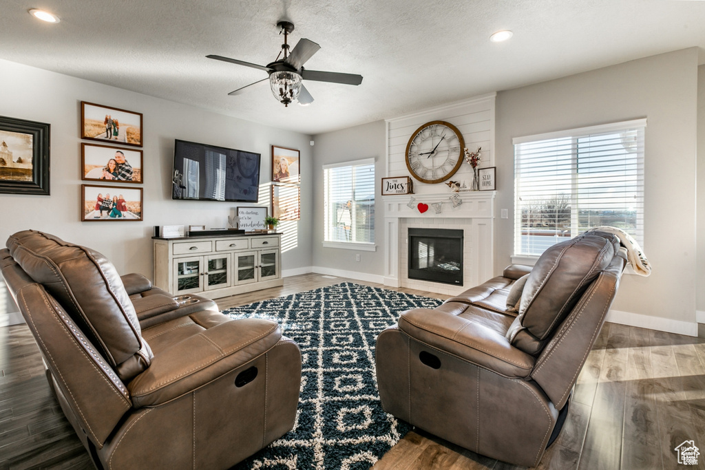 Living room with healthy amount of natural light, a ceiling fan, wood finished floors, a large fireplace, and recessed lighting