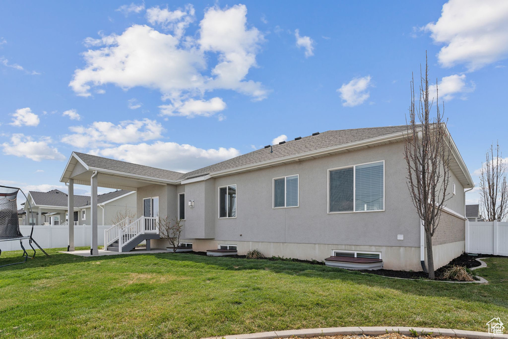 Rear view of property featuring stucco siding and a trampoline