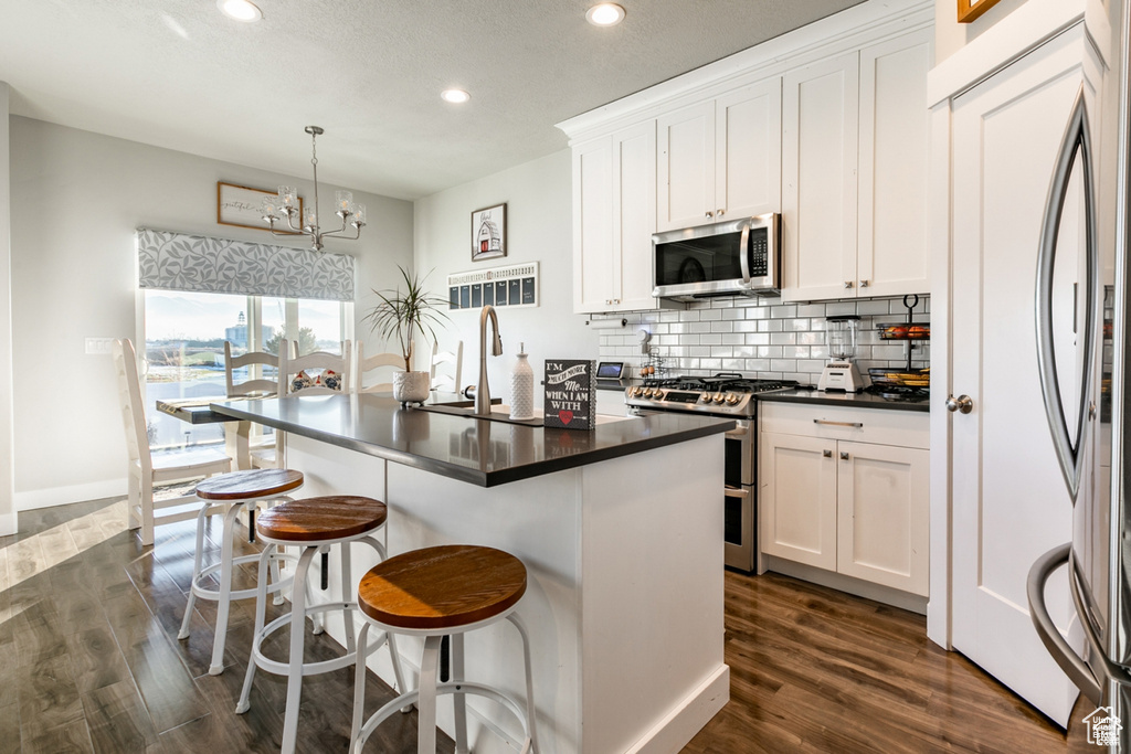 Kitchen featuring stainless steel appliances, recessed lighting, dark countertops, dark wood-style floors, and backsplash
