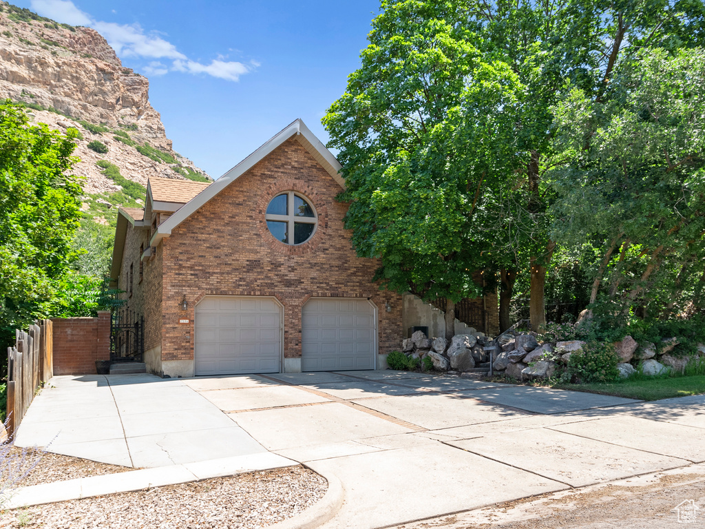View of front facade with a garage, driveway, and brick siding