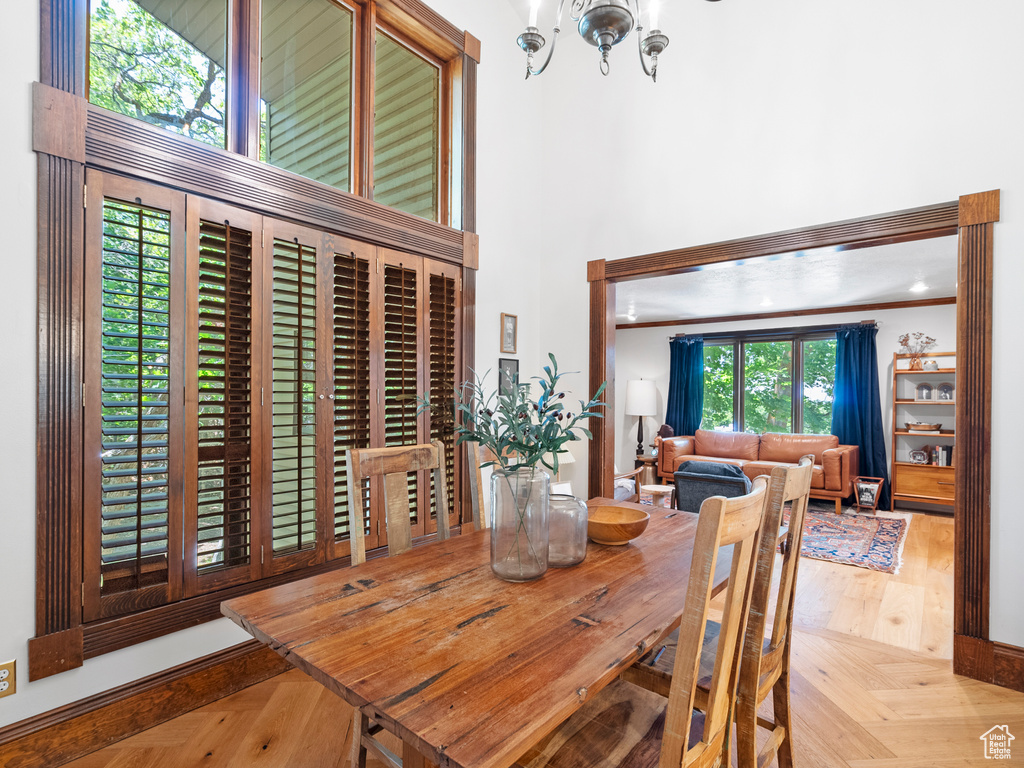 Dining space featuring a high ceiling, a chandelier, and wood finished floors